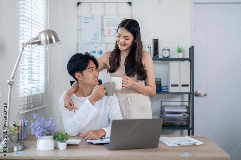 An Asian couple shares a light-hearted moment during a coffee break at their home office, with smiles and a relaxed atmosphere. An Asian couple shares a light-hearted moment during a coffee break at their home office, with smiles and a relaxed atmosphere.