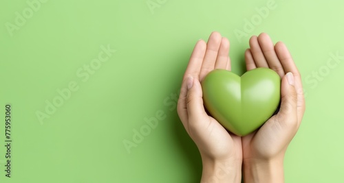 Hands of a woman holding a green heart, symbolizing happiness, health care, saving the world, donation, and family insurance concept