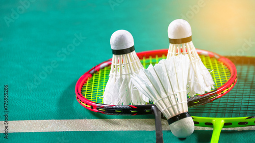 White badminton shuttlecocks and badminton rackets on green floor indoor badminton court soft and selective focus on shuttlecocks and the rackets