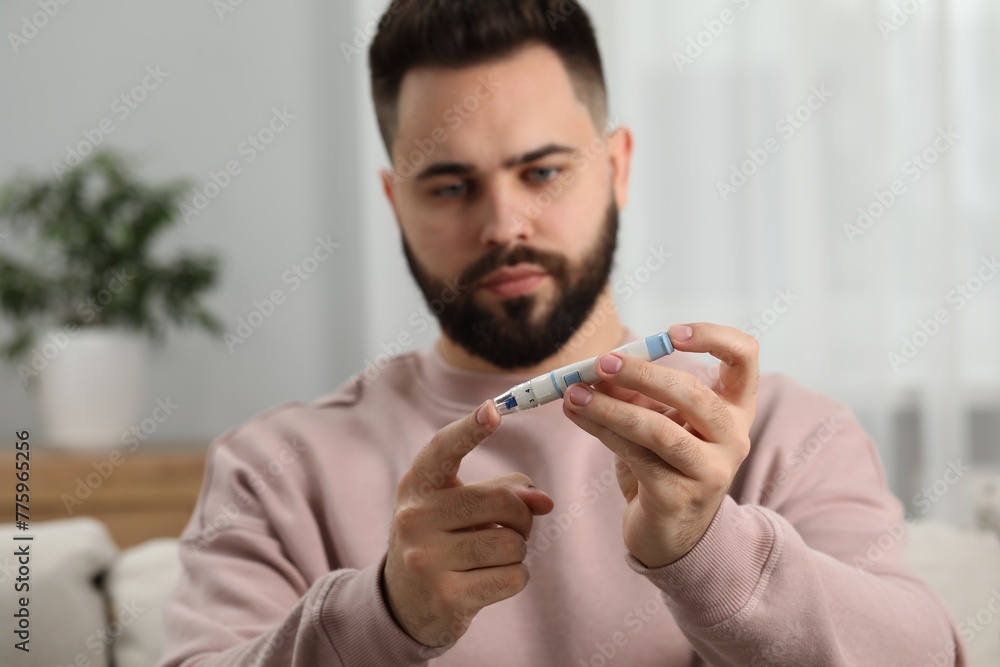 Diabetes test. Man checking blood sugar level with lancet pen at home, selective focus Diabetes test. Man checking blood sugar level with lancet pen at home, selective focus