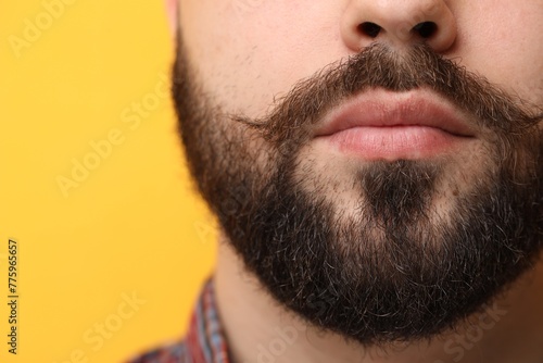 Handsome man with mustache on yellow background, closeup
