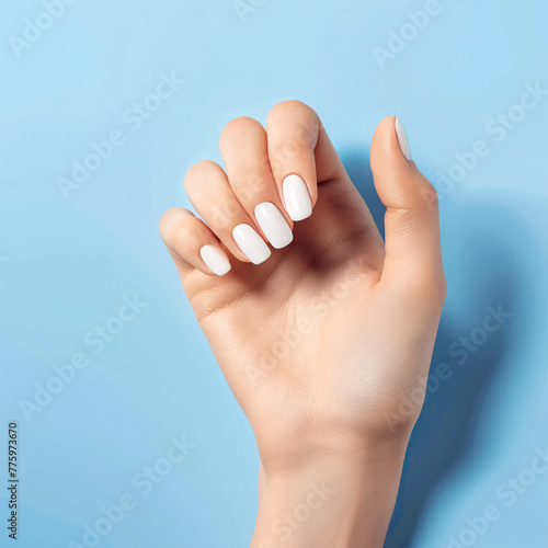 A hand with white manicured nails against a calming pastel blue background. photo