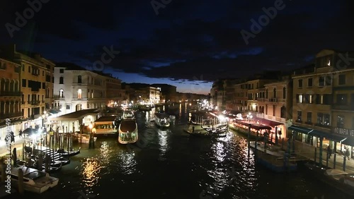 Aerial footage of the Rialto bridge in Venice, Italy, with boats at night