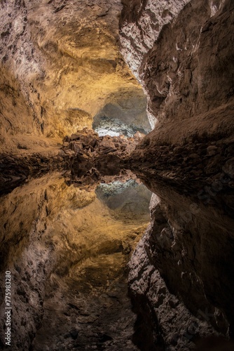 Vertical shot of a hidden cave with still water reflecting the cave walls