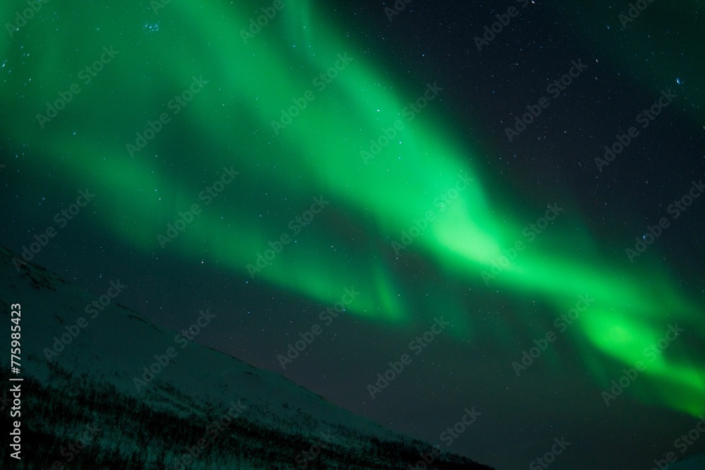 Beautiful shot of bright green aurora northern lights over mountains in Norway