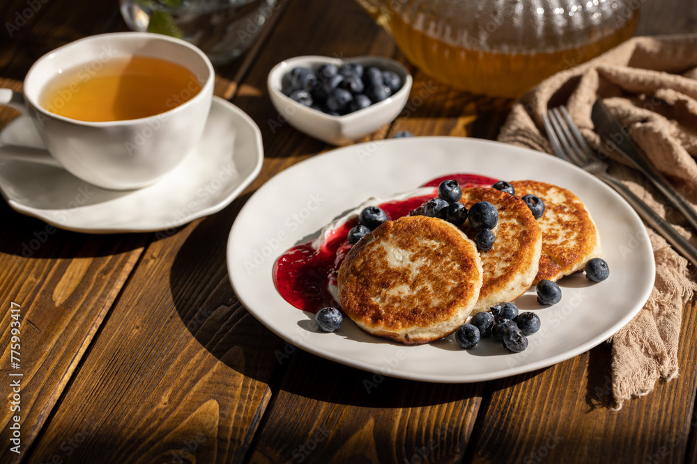 Breakfast with cheesecakes, pancakes with sour cream, mashed berries and fresh blueberries Breakfast with cheesecakes, pancakes with sour cream, mashed berries and fresh blueberries