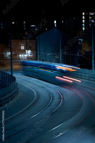 Photography Vertical long exposure of a tram on a calm street in Oslo at night