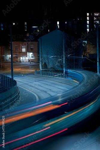 Vertical long exposure of a tram passing through a calm street in Oslo at night