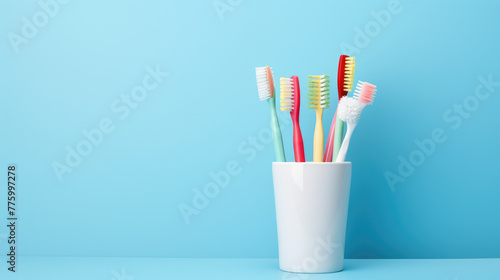 Different toothbrushes in holder on light blue background Space for text © Mongkol