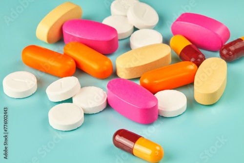 Closeup shot of a pile of scattered colorful medicines on the cyan background