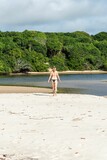 Vertical shot of a young Caucasian woman walking on the beach in Praia do Guaibim, Bahia, Brazil
