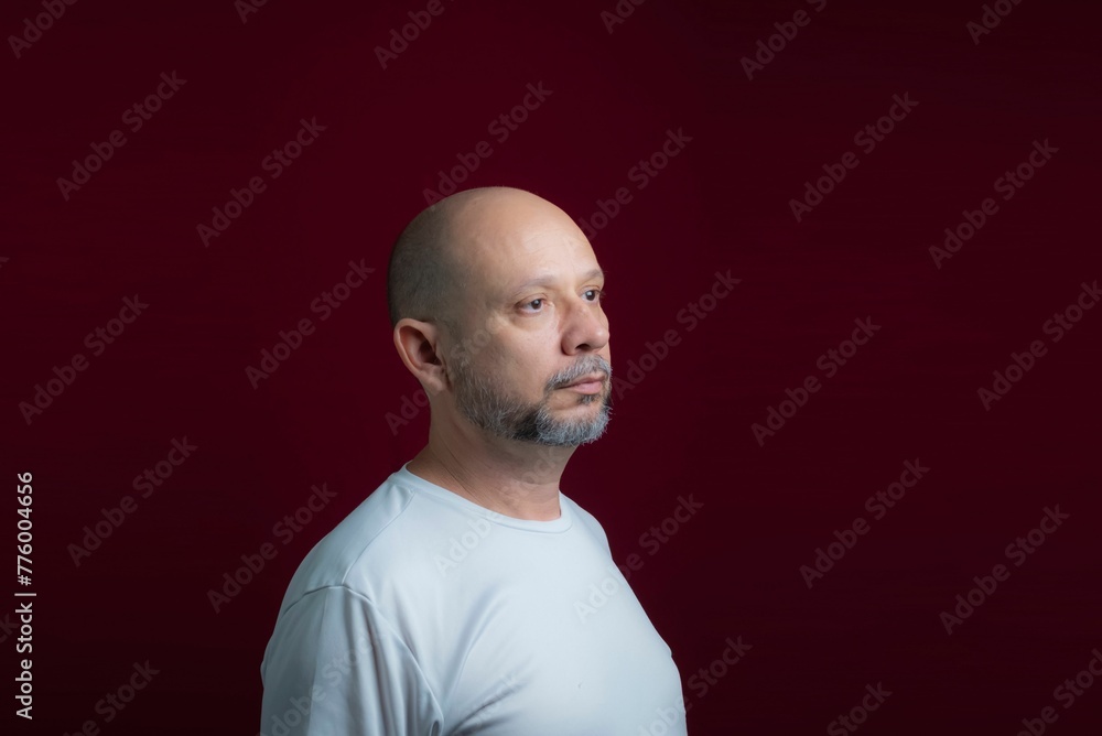 Obraz premium Portrait of a bald bearded man looking up against a red background