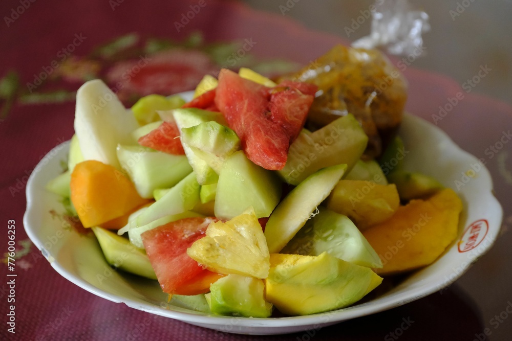 White plate of Fruit salad with spicy peanut sauce, consisting of pineapple, mango, guava