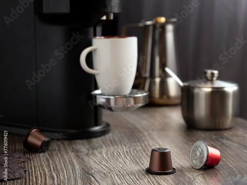 Capsules for making coffee in a coffee machine lie on the table against the background of a home kitchen.