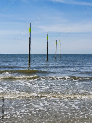 Vertical shot of the wooden poles in the North Sea in St. Peter-Ording against the blue sky