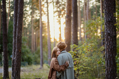couple in love in the forest at sunset on a date hugging in a coat in the summer. Cinematic love story © velimir