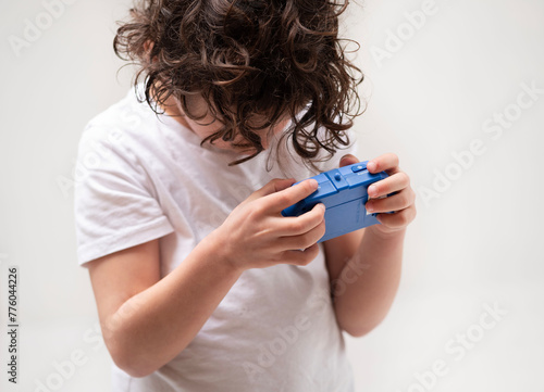 Curlyhaired boy holds electric blue gadget in arm