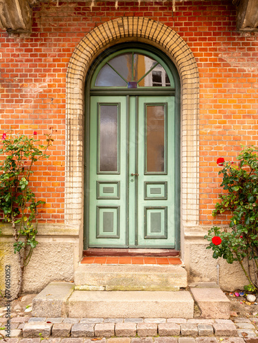 Front view of green door with roses in old town of Mariager, Nordjylland, Denmark