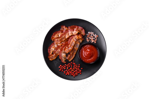 Delicious fresh fried bacon with salt and spices on a dark background