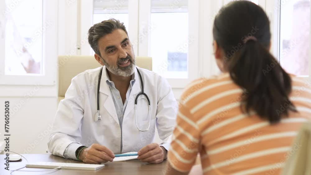 Confident male doctor talking to patient in clinic during daytime Confident male doctor talking to patient in clinic during daytime