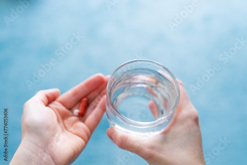 Woman's hands about to take a pill, glass of water and copy space.
