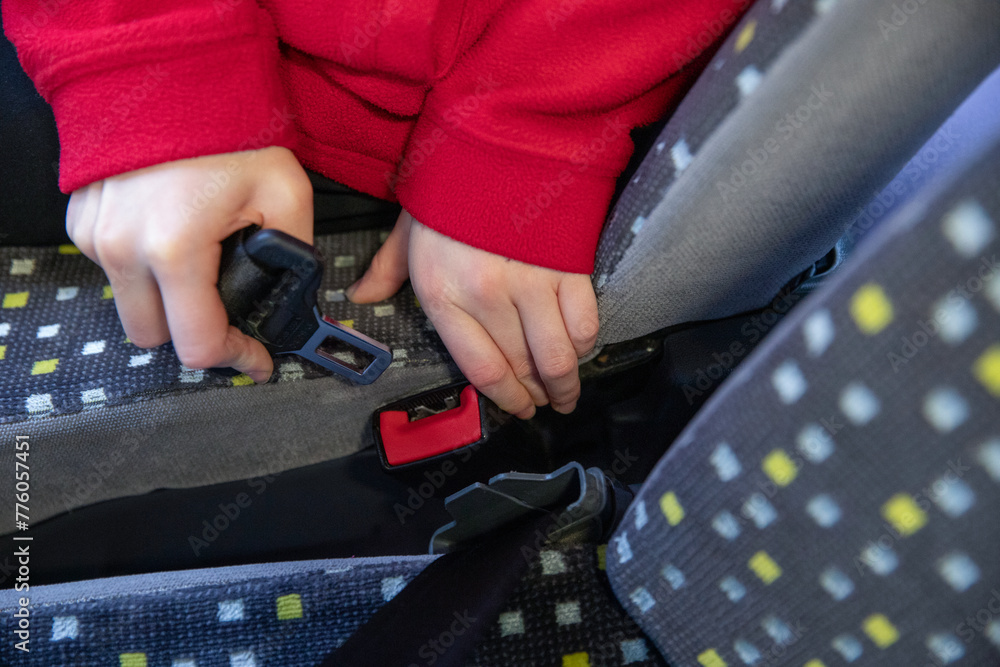 Gros plan d'un enfant attachant sa ceinture de sécurité dans un bus - obrazy, fototapety, plakaty 