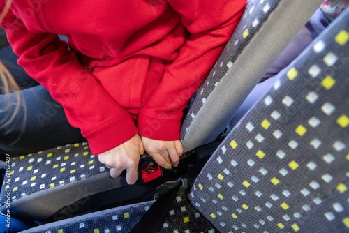 Gros plan d'un enfant attachant sa ceinture de sécurité dans un bus photo