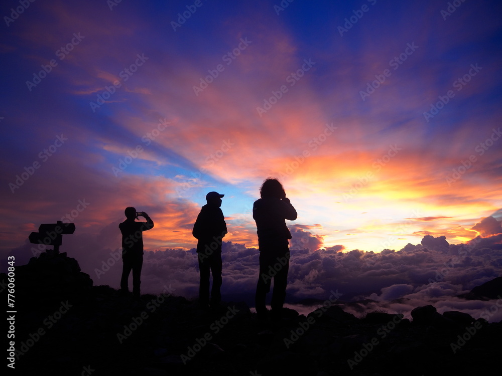 雲海に沈む夕日に見惚れる登山者たち