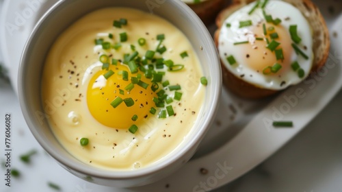 A bowl of creamy and decadent hollandaise sauce served alongside eggs Benedict