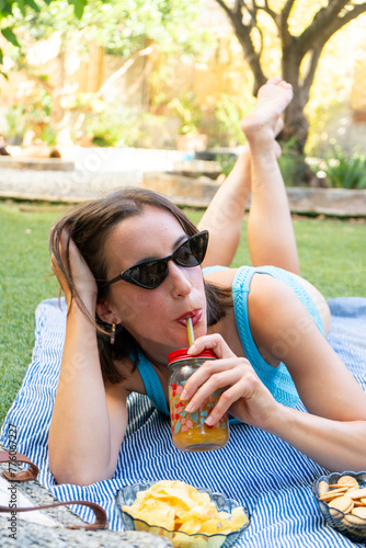 portrait of a smiling girl sunbathing and drinking a juice 