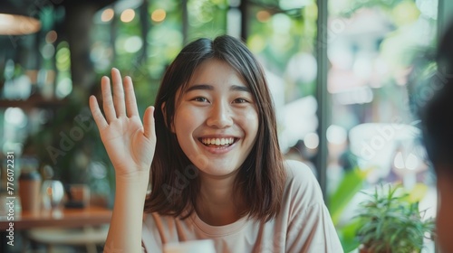 Cheerful Asian Student Waving Hello in Cafe