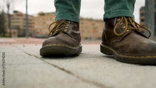 A man in brown leather boots walks down the street and steps in dog poop. Some owners have not picked up their pet's droppings. Bad luck or good luck, depending on how you look at it. photo