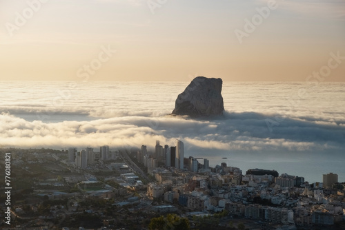 View of the Ifach rock and the city of Calpe at dawn. Low clouds.