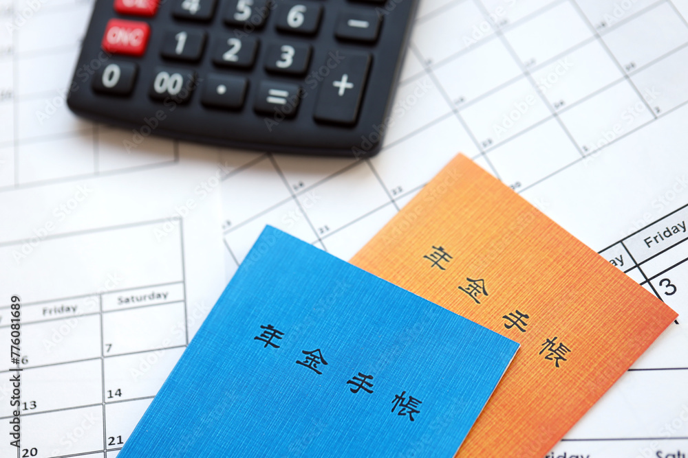 Japanese pension insurance booklets on table with calculator on table close up Japanese pension insurance booklets on table with calculator on table close up