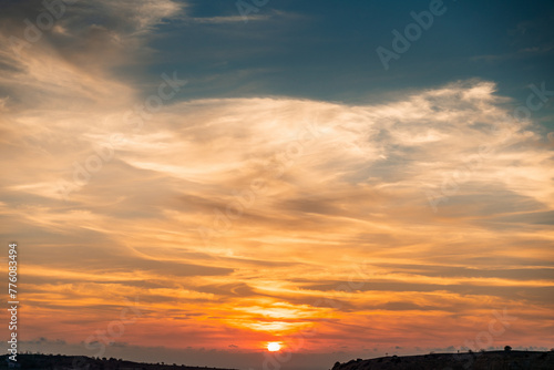 beautiful sunset with a large sun in the sky. The sky is filled with clouds and the sun is setting in the distance.