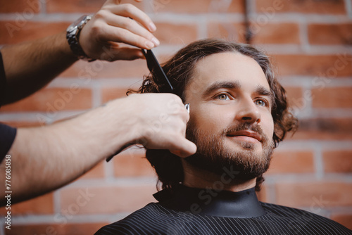 Happy hipster man in barber chair getting haircut from barbershop, warm toning
