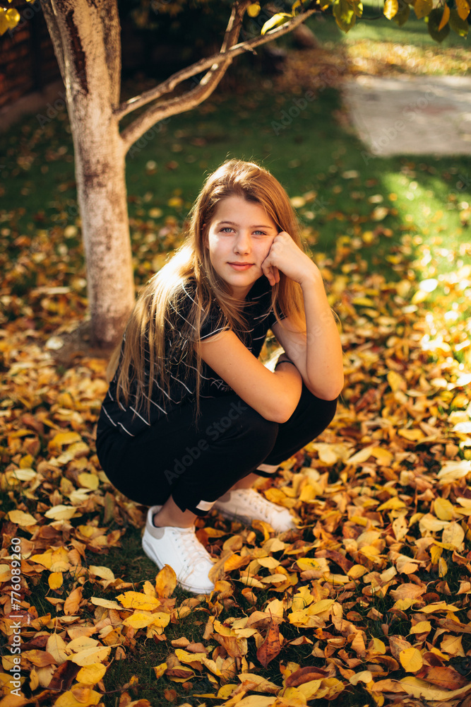 a beautiful blonde girl sits on the grass covered with fallen yellow leaves. golden autumn and fallen leaves. a beautiful blonde girl sits on the grass covered with fallen yellow leaves. golden autumn and fallen leaves.