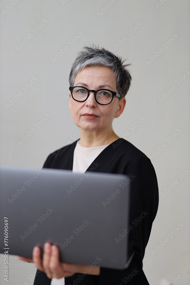 A mature businesswoman works on her laptop, embodying professionalism and digital proficiency. A mature businesswoman works on her laptop, embodying professionalism and digital proficiency.