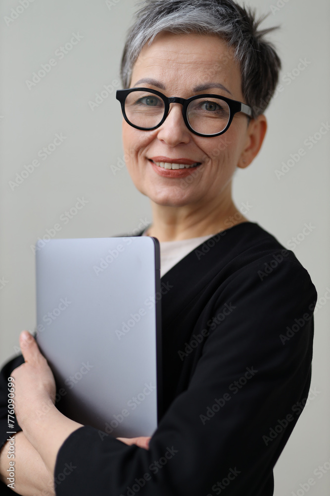 mature, positive woman holds a laptop, radiating professionalism and happiness mature, positive woman holds a laptop, radiating professionalism and happiness