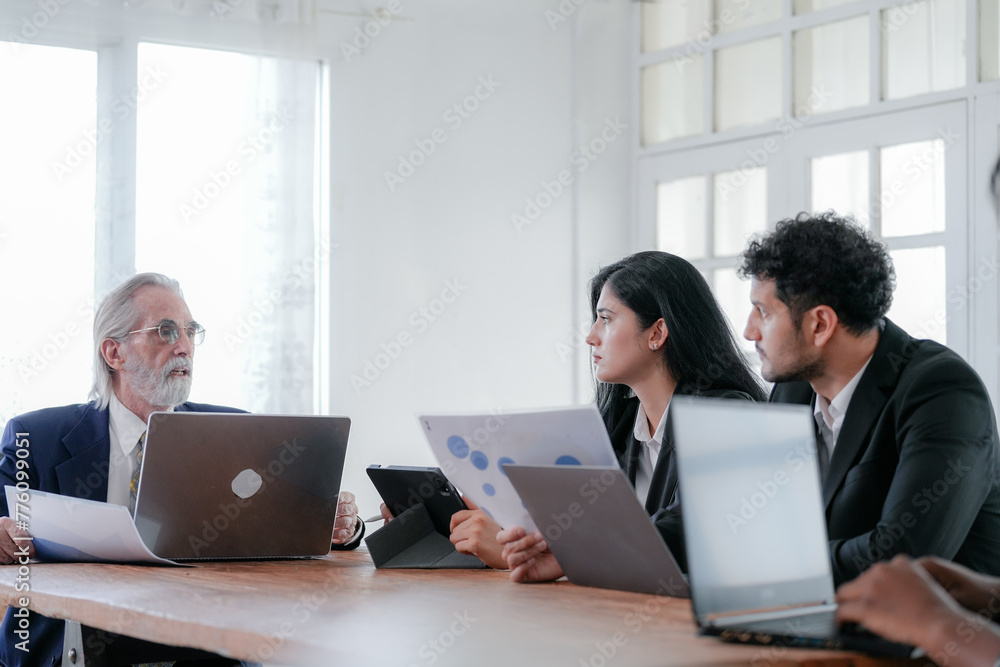 Corporate business team and manager in meeting. Diversity of business people of African and Latin women and Caucasian men are working together. Senior boss are consulting team at clean interior room. Corporate business team and manager in meeting. Diversity of business people of African and Latin women and Caucasian men are working together. Senior boss are consulting team at clean interior room.