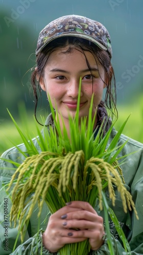 Young Woman Smiling in Raincoat Holding Freshly Harvested Rice in Rain photo