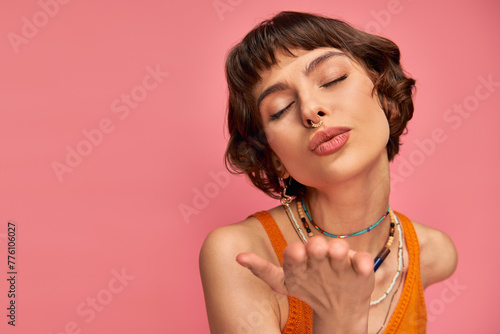 Bild auf Leinwand flirty young woman with nose piercing and short brunette hair showing kiss on pi