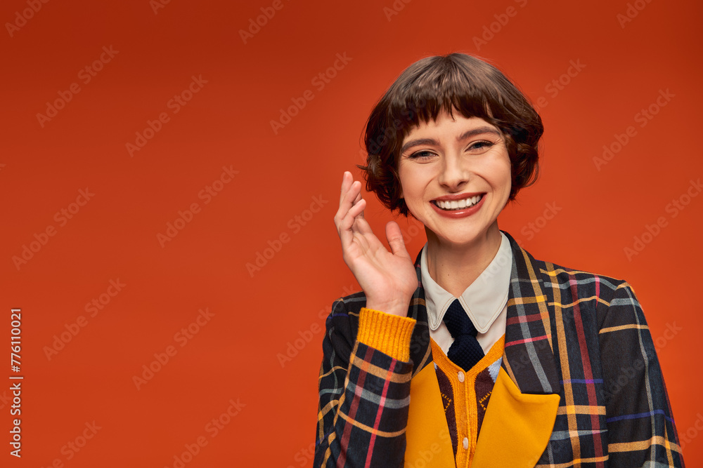 optimistic college girl in checkered uniform waving hand on orange background, happy student life optimistic college girl in checkered uniform waving hand on orange background, happy student life