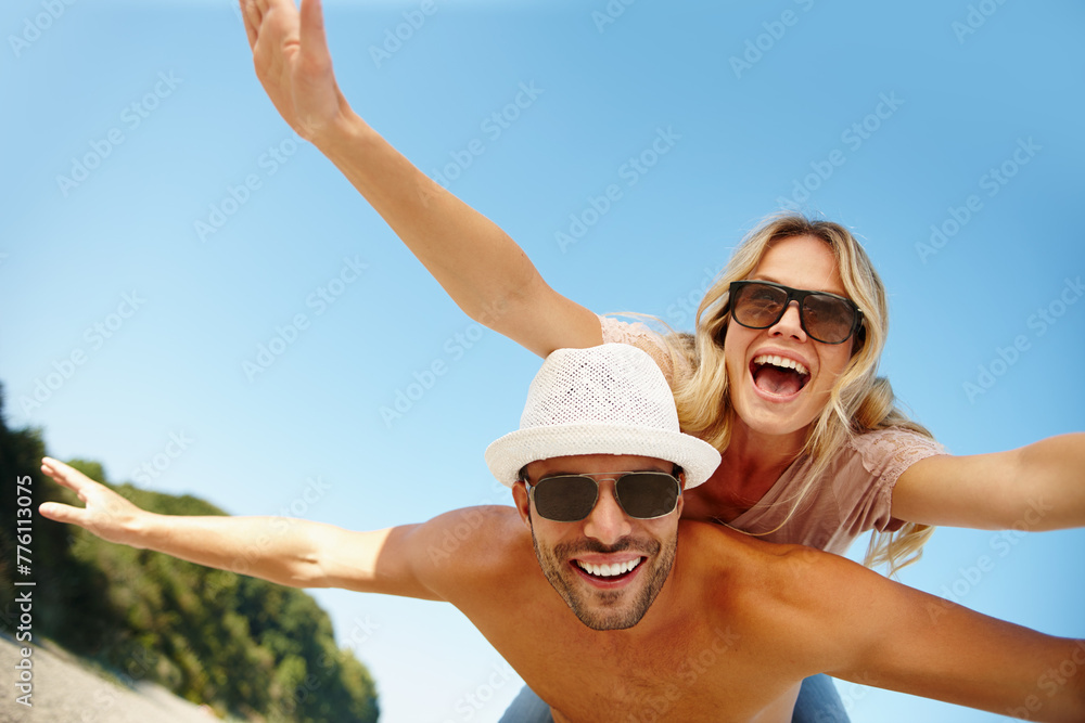 Couple, sunglasses and piggyback on vacation, fun and peace at beach or game by blue sky. People, happy and tropical island for bonding on weekend, outdoor nature and love for marriage or romance