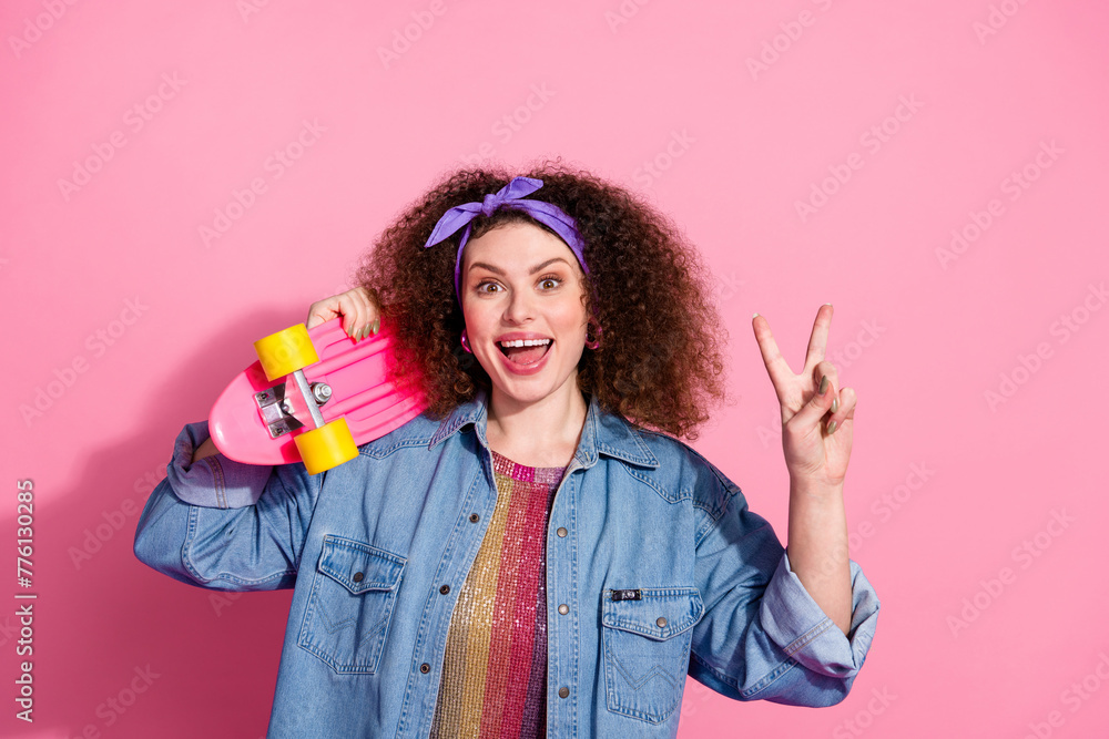 Photo of cool cheerful lady dressed denim outfit showing v-sign holding long board empty space isolated pink color background Photo of cool cheerful lady dressed denim outfit showing v-sign holding long board empty space isolated pink color background