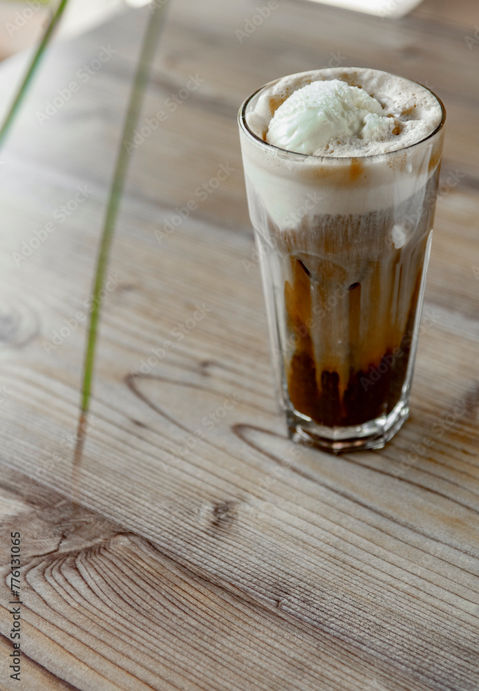 Iced coffee with whipped cream in a glass on a wooden table Iced coffee with whipped cream in a glass on a wooden table