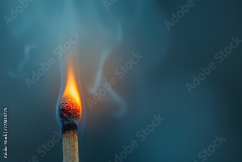 Burning matchstick with smoke against a cool blue background