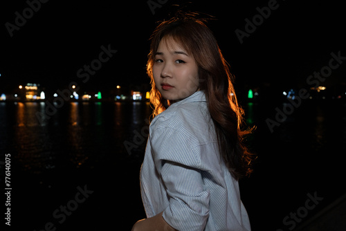Stylish Young Vietnamese Woman in Striped Shirt Posing by the Lake at Night