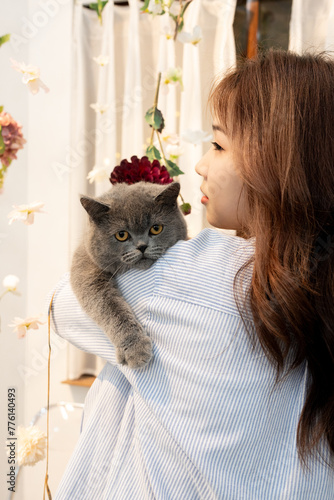 Stylish Young Vietnamese Woman in Striped Shirt Embracing Cat Poses at Coffee Shop - SEO-Friendly Title