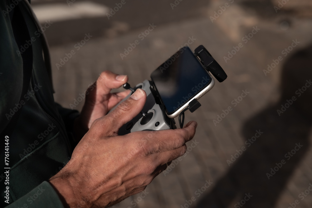 man's hands with radio remote control operating drone in mid-flight with cell phone man's hands with radio remote control operating drone in mid-flight with cell phone